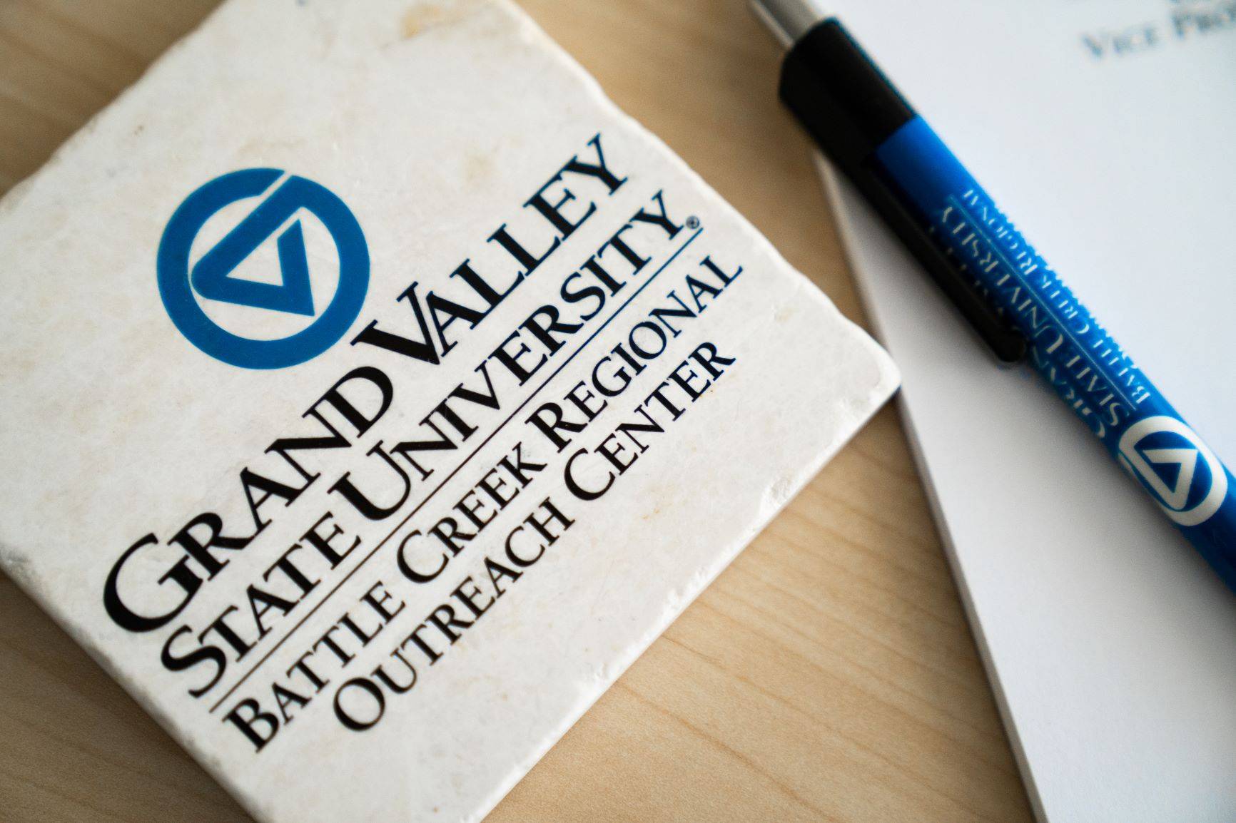 grand valley logo coaster on table with pen